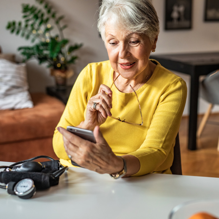 Ältere Dame schaut auf ihr Smartphone