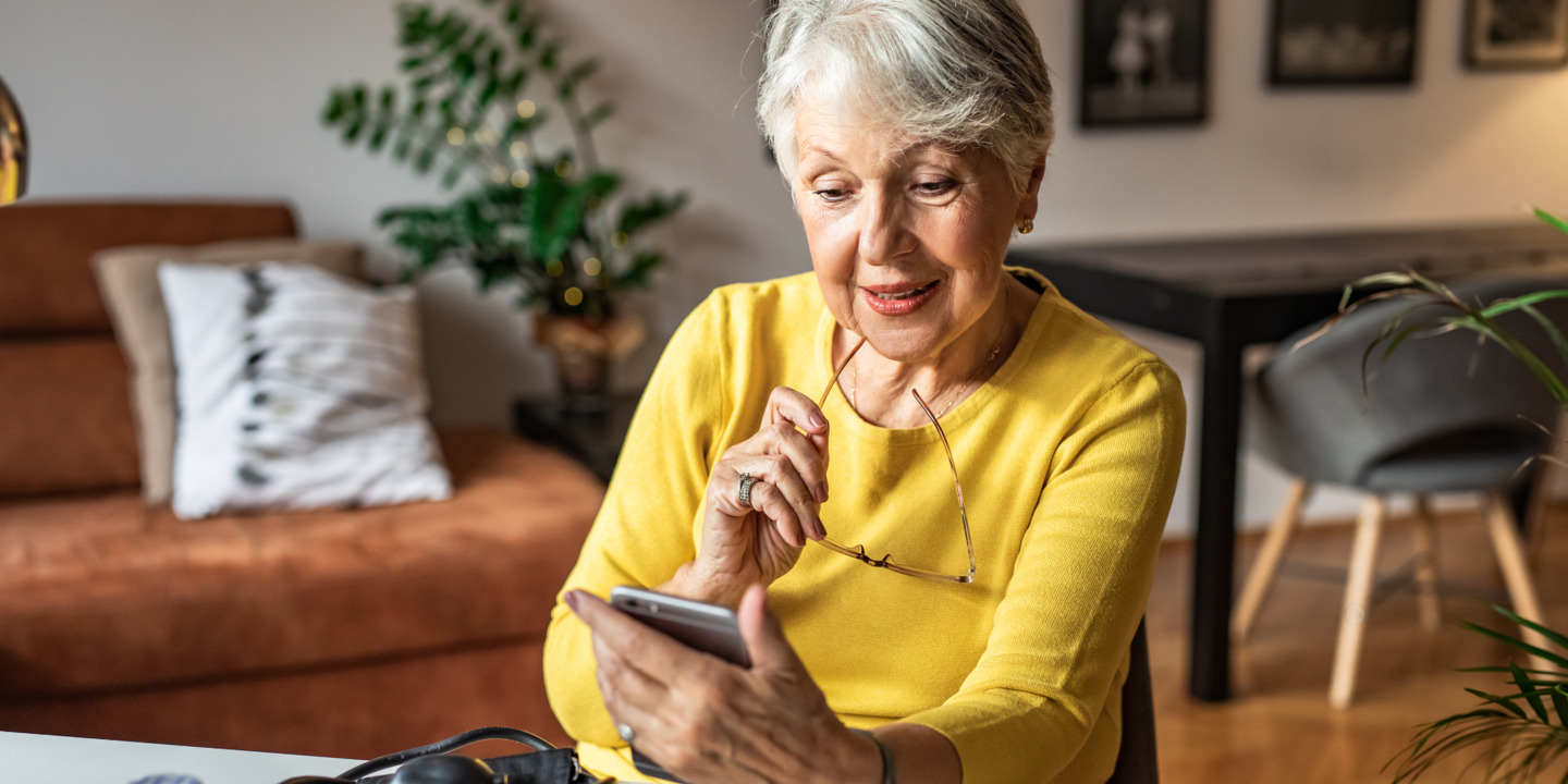 Ältere Dame schaut auf ihr Smartphone