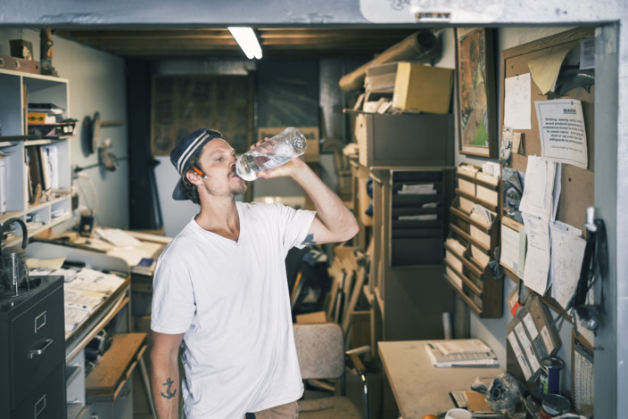 verschwitzter Handwerker trinkt Wasser