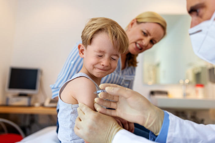 Junge schließt während der Impfung beim Kinderarzt die Augen