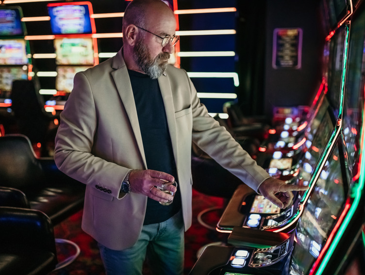 Mann steht am Spielautomat in der Spielhalle