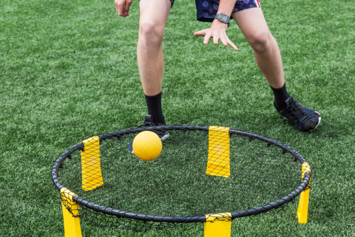 Person spielt Spikeball auf dem Rasen