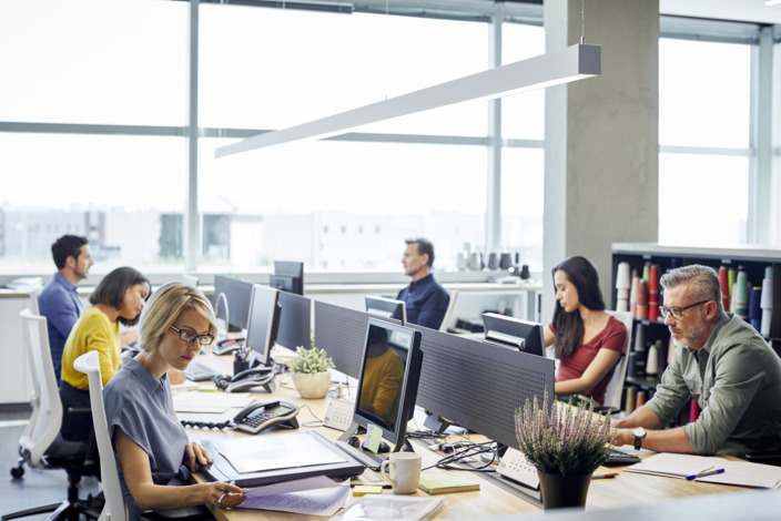 Menschen sitzen an einem großen Tisch im Büro.