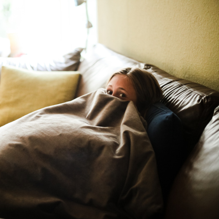 Frau versteckt sich unter einer Decke