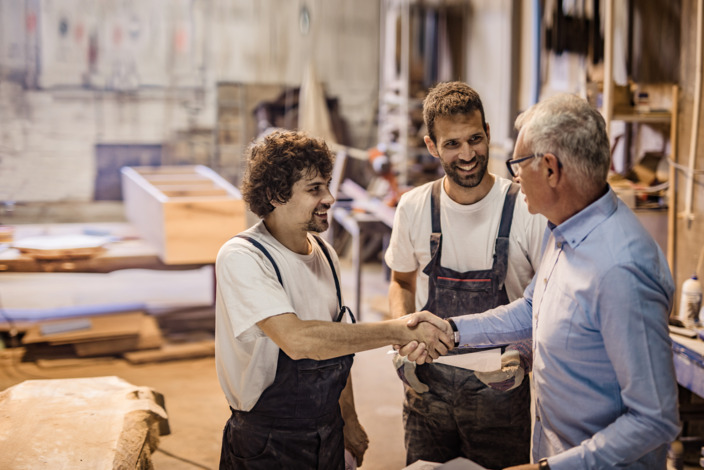 Zwei Handwerker im Gespräch mit einem Kunden