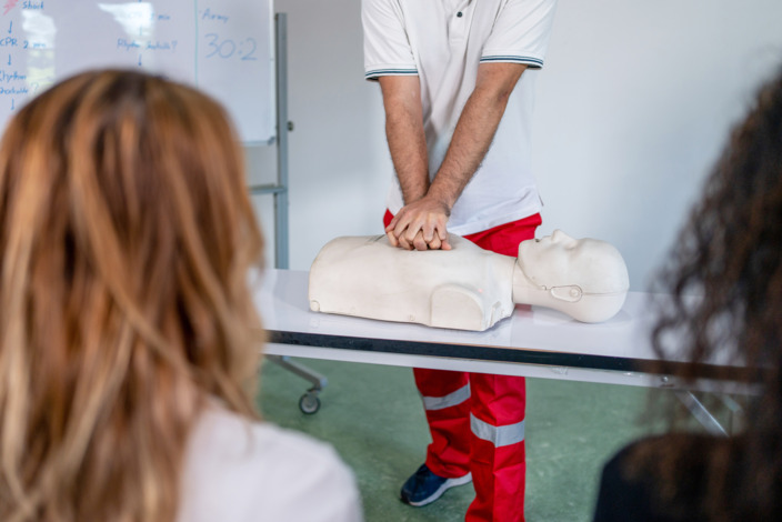 Rettungssanitäter demonstriert eine Herzmassage an einer Erste-Hilfe-Puppe