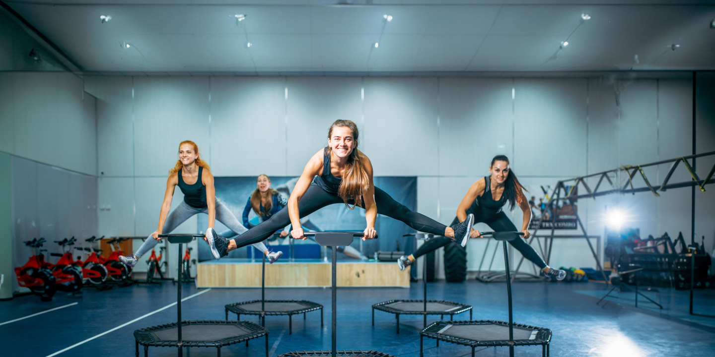 Frauen, die in einer Turnhalle an ihren Trampolinen Jumping Fitness betreiben