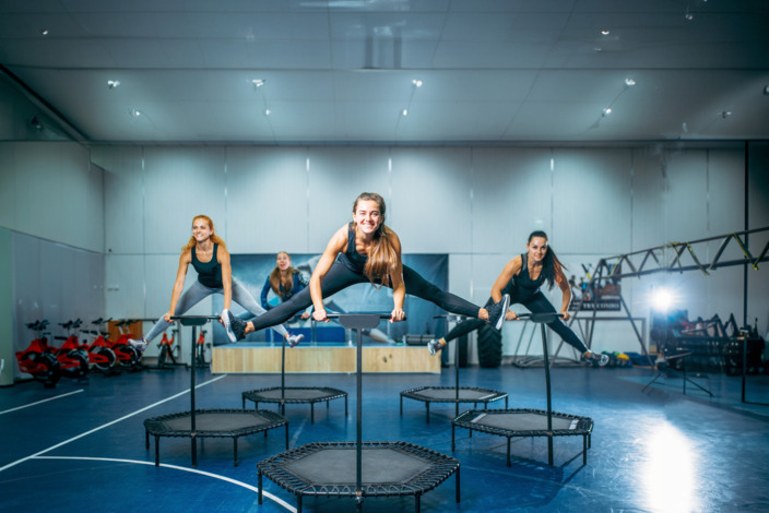 Frauen, die in einer Turnhalle auf Trampolinen springen