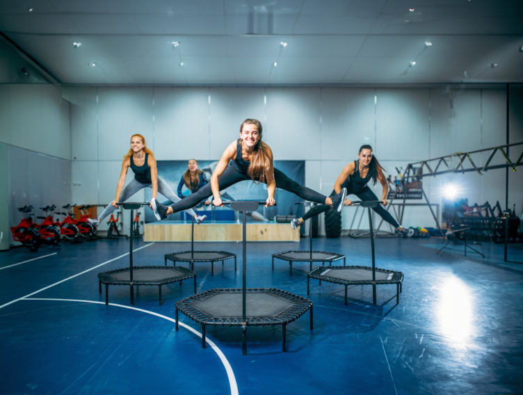 Damen im Fitnessstudio machen Übungen am Trampolin