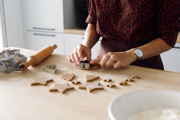 Eine Person sticht mit Förmchen Plätzchen in verschiedenen Formen aus.