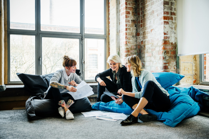 Drei Frauen sitzen im Büro und arbeiten gemeinsam.