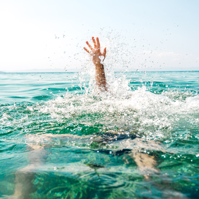 Eine Hand einer Person schaut aus dem Wasser raus, weil sie zu ertrinken droht