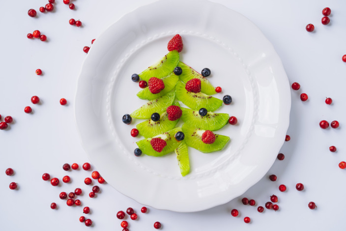 dekorierter Teller mit einem gelegten Tannenbaum aus Kiwi und Beeren