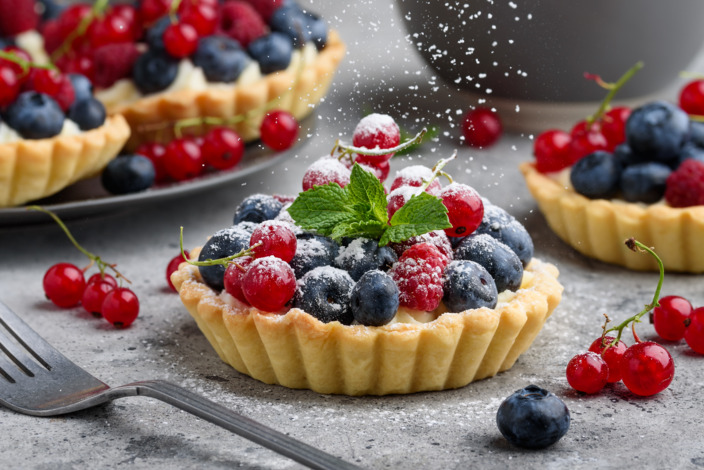 Ein veganes Tartelette mit Himbeeren, Heidelbeeren und Pfefferminzblättern.