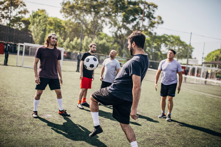 eine Gruppe Männer spielt Fußball auf einem Sportplatz