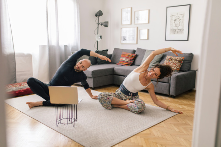 Paar macht Sport im Wohnzimmer vor dem Laptop