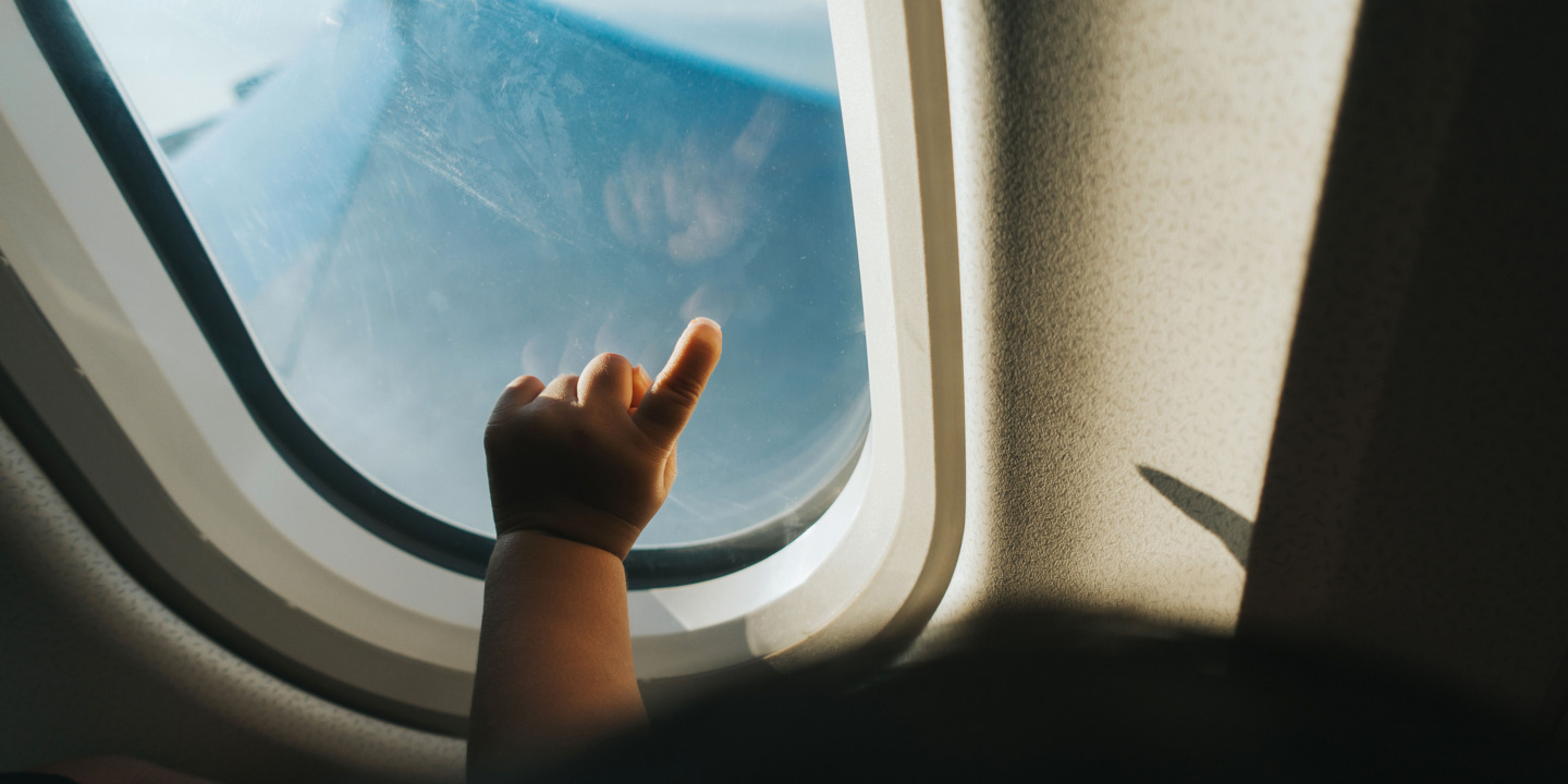 Die Hand eines Babys vor einem Flugzeugfenster