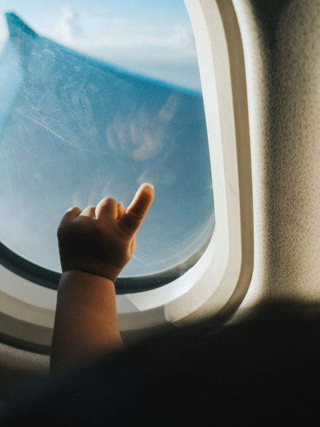 Die Hand eines Babys vor einem Flugzeugfenster