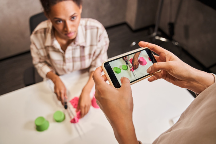 Frau filmt mit Smartphone Bloggerin, die kinetischen Sand schneidet