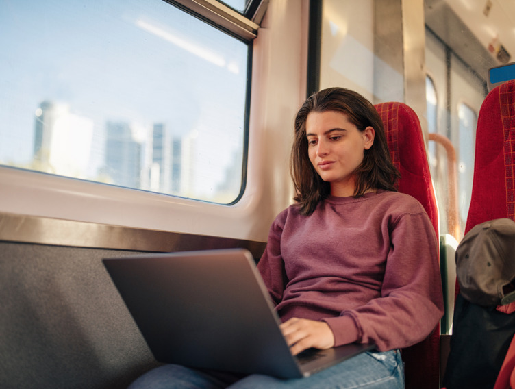 Frau im Zug, die am Laptop arbeitet