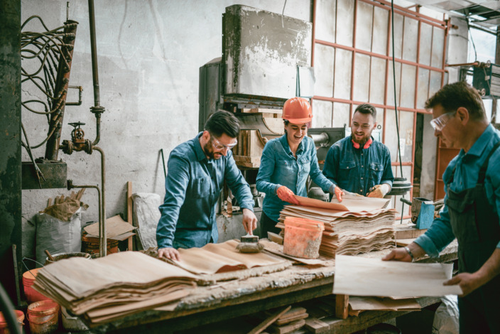 Vier Handwerker lachen zusammen in der Werkstatt